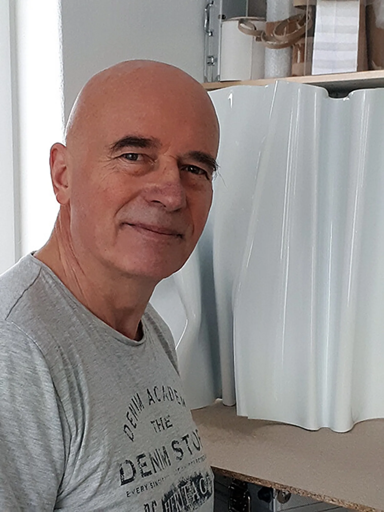 Bildhauer Kuno Vollet in seinem Atelier neben einer weißen, wellenförmigen Skulptur