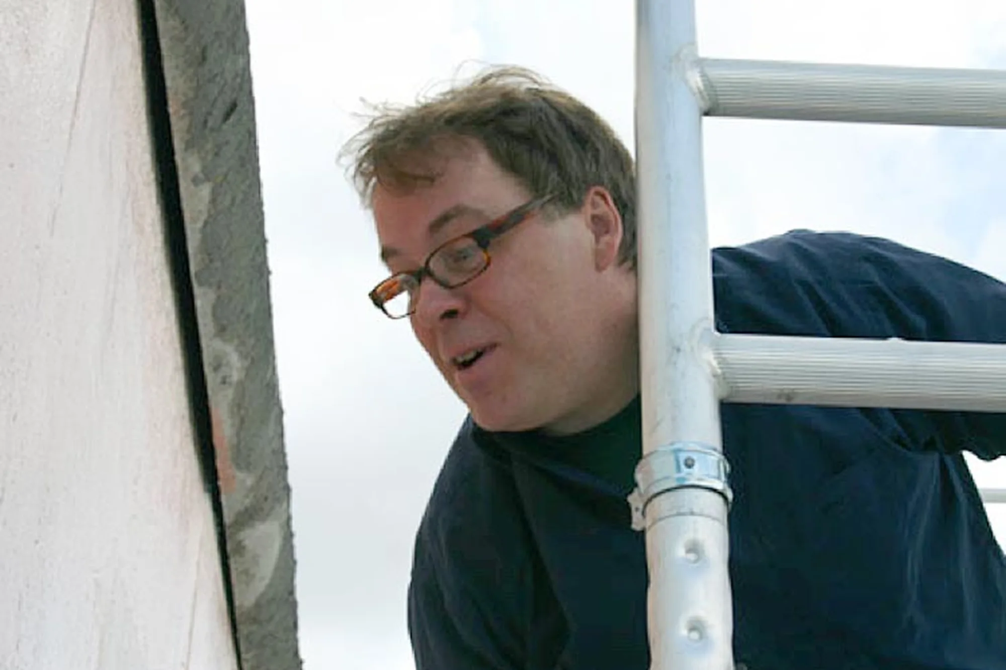 Bildhauer Pierre-Paul Maillé mit Brille bei der Arbeit auf einem Gerüst