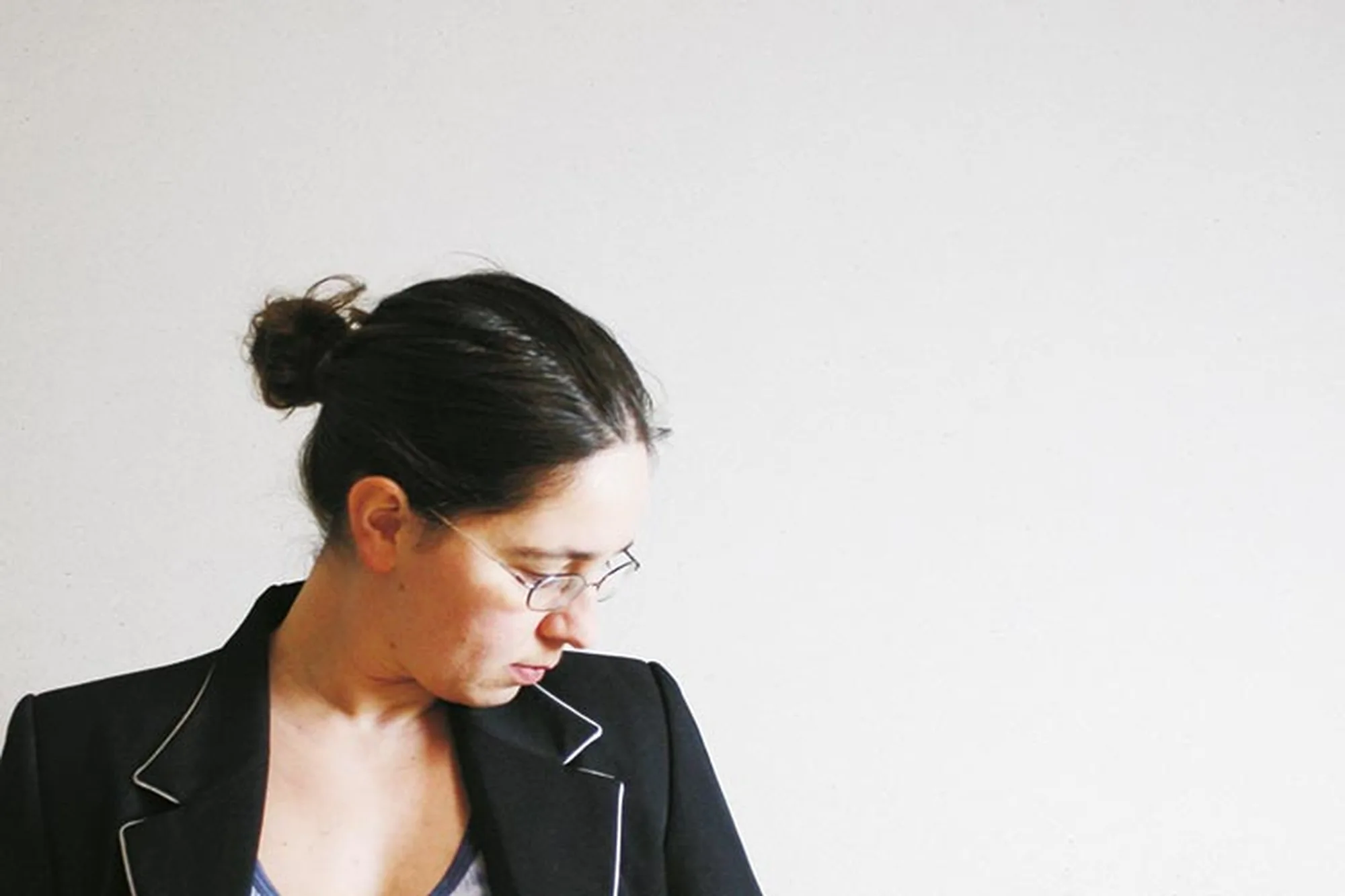 Bildhauerin Susanne Kraißer im Profil mit Brille und dunklem Blazer vor heller Wand