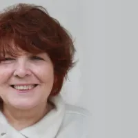 Porträt der Bildhauerin Jana Pfeifer mit kurzem rotbraunem Haar, lächelnd vor hellem Hintergrund