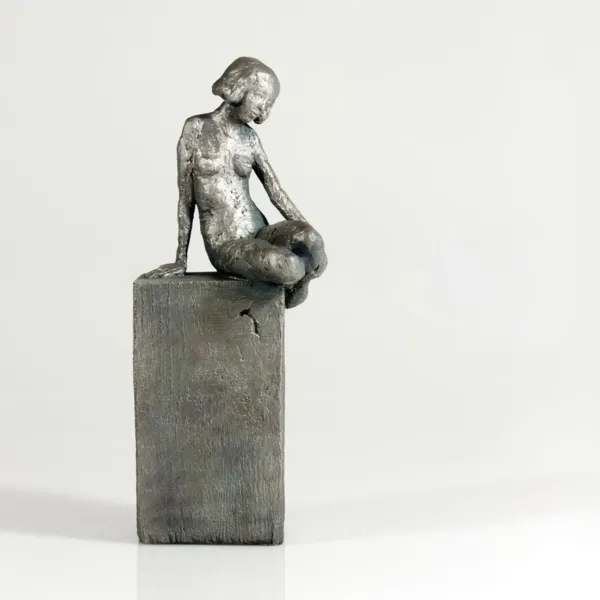 Silberskulptur einer sitzenden Frauenfigur auf hohem Sockel