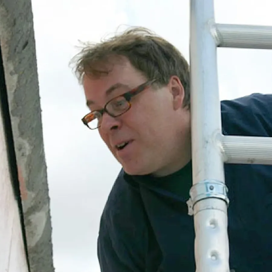Bildhauer Pierre-Paul Maillé mit Brille bei der Arbeit auf einem Gerüst